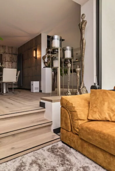 Woonkamer in de showroom Heemskerk met lichte houten vloer, trede en okergele bank