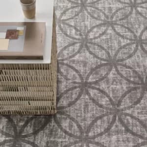 Grijs tapijt met cirkelpatroon en rotan bijzettafel in de showroom Nieuw-Vennep