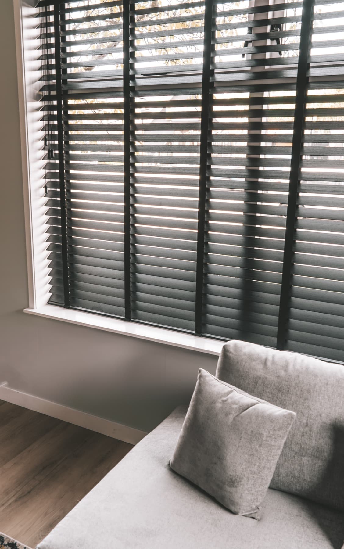 Donker houten jaloezieën in een woonkamer bij een loungebank