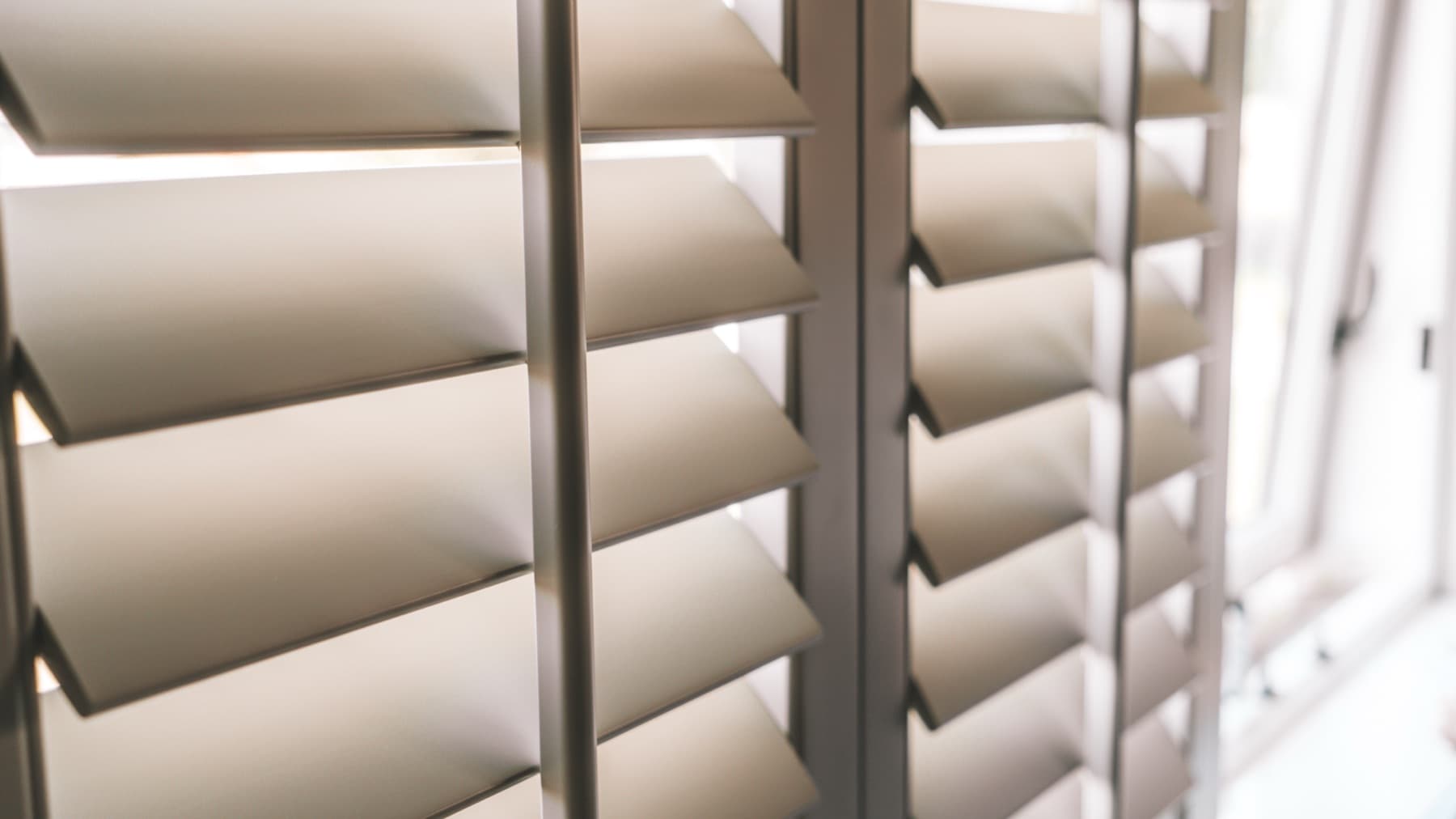 Detailopname van crèmekleurige shutters in zacht licht