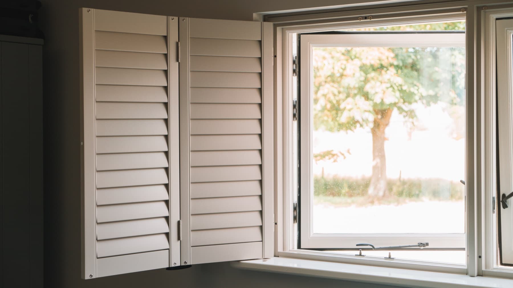 Shutter half geopend met uitzicht op een boom in de tuin
